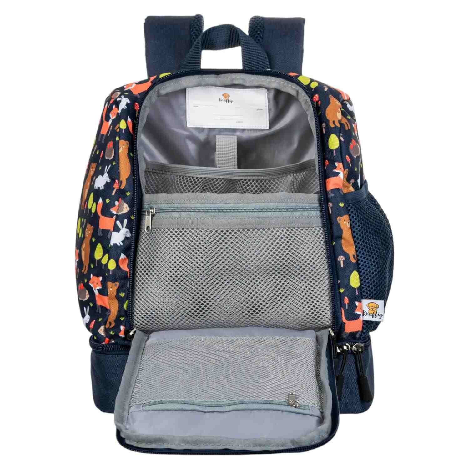 Frontalansicht eines gut organisierten, blauen Kinderrucksacks mit einem niedlichen Fuchs-Motiv. Das Bild zeigt mehrere geöffnete Reißverschlussfächer: Ein kleineres Frontfach und das geräumige Hauptfach sind sichtbar. In der mittleren Reißverschlusstasche ist ein transparentes Einschubfach mit einem beschrifteten Namensschild eingenäht. Der Rucksack verfügt über elastische Kordelzüge und mehrere kleine Fächer, die für Ordnung sorgen. Der strapazierfähige Stoff und die verstellbaren, gepolsterten Schultergu