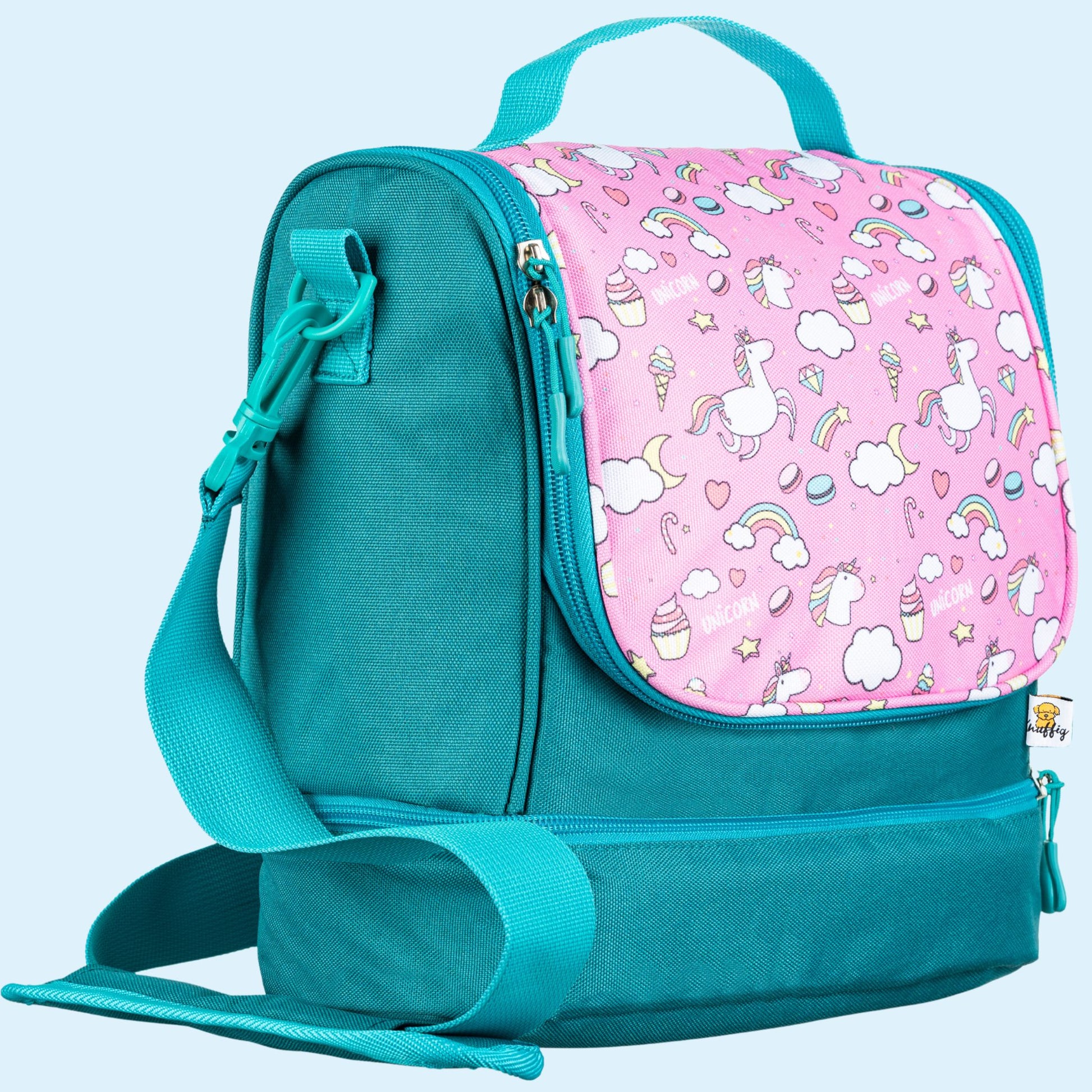 Detailansicht der geöffneten, multifunktionalen Umhängetasche für Kinder im rosa Einhorn-Design. Die Tasche zeigt ihre durchdachte Aufteilung: Ein spezielles, gepolstertes Fach hält die Toniebox sicher fest. Daneben ist eine farblich passende Lunchbox verstaut. Der geräumige Innenraum bietet Platz für weiteres Zubehör wie Tonie-Figuren, einen kleinen Notizblock oder eine Trinkflasche. Die Darstellung unterstreicht die ordentliche Organisation des Audio-Equipments und der Verpflegung für unterwegs, umhüllt v