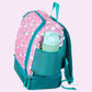 Die Seitenansicht des rosa Einhorn-Rucksacks zeigt das elastische Netzfach, in dem eine Trinkflasche sicher verstaut ist. Das Profil der Tasche hebt das glitzernde Horn auf der Vorderseite und die farblich abgesetzte Mähne hervor. Man sieht deutlich den stabilen Stand der Tasche und die hochwertige Verarbeitung des Canvas-Stoffs sowie den leichtgängigen Reißverschluss für kleine Kinderhände.