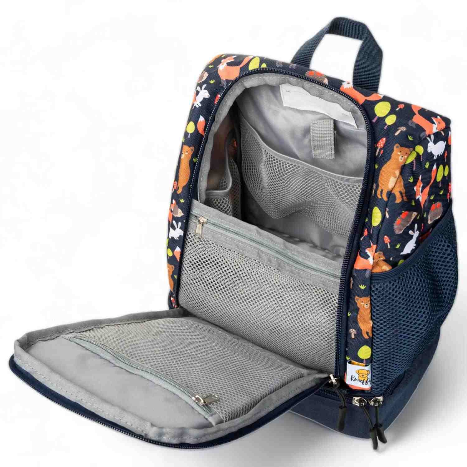 Innenansicht eines blauen Kinderrucksacks mit Fokus auf das Ordnungssystem: Ein elastisches Netzfach verstaut sicher mehrere Tonie-Figuren, während eine spezielle Klettverschluss-Schlaufe darüber zur Befestigung von Kinderkopfhörern dient. Das helle Innenfutter sorgt für Übersichtlichkeit im Hauptfach.