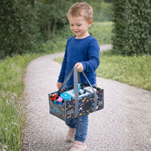 in kleiner Junge trägt die graue Dinosaurier-Transporttasche am praktischen Handgriff; das kompakte Design ist ideal für Kinderhände und den Einsatz unterwegs im Park oder auf Reisen.