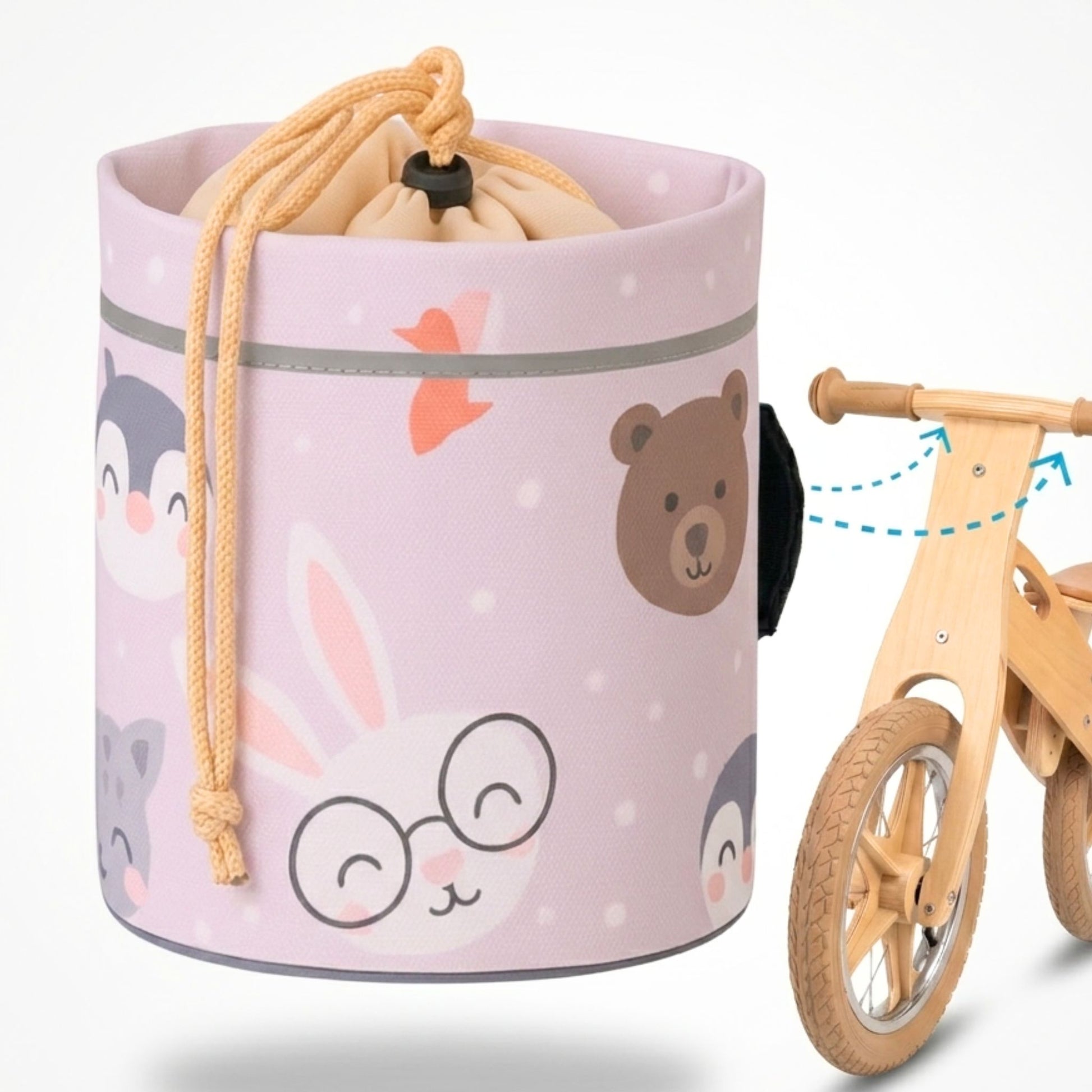 Eine zylindrische, beige Lenkertasche für Kinderfahrräder mit niedlichen Tierillustrationen (Hase mit Brille, Bär, Pinguin) und Kordelzugverschluss, daneben ein hölzernes Laufrad mit Pfeilen, die die Befestigung am Lenker illustrieren