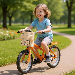 Kind fährt mit orangefarbenem Fahrrad und beige Knuffig Fahrradtasche mit Hundemotiv am Lenker im Park