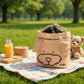 Beige Knuffig Lenkertasche mit Hundemotiv auf einer Picknickdecke im Park, neben Teddybär und Snacks