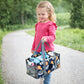 Ein Mädchen trägt die gelbe Löwen-Transporttasche am verstärkten Handgriff; die kompakte Tragetasche ist ideal auf Kinderhände zugeschnitten und ermöglicht den einfachen Transport der Toniebox.