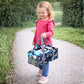 Ein kleines Mädchen hält die rosa Prinzessinnen-Tragetasche am verstärkten Handgriff; das liebevolle Design und die kindgerechte Größe machen sie zum idealen Accessoire für kleine Fans und den sicheren Transport der Toniebox.
